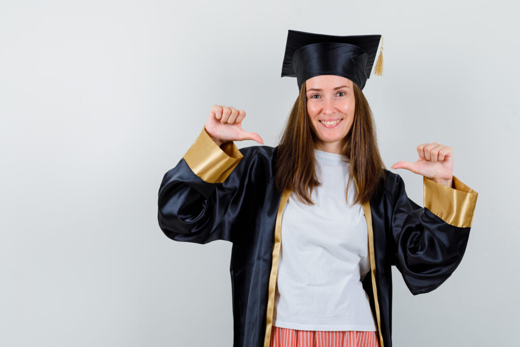 A proud Vancouver grad in cap and gown smiling and pointing to herself — ready to celebrate with a photo booth rental.